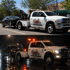 Towing Sandy wheel-lift tow truck transporting a disabled sedan during daytime and nighttime roadside towing service.