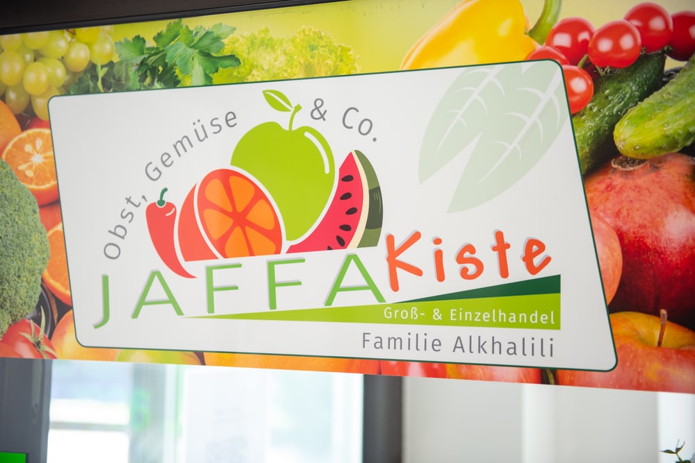 Jaffa Kiste Obst & Gemüse Logo mit Apfel, Orange, Wassermelone und dem Text "Groß- & Einzelhandel Familie Alkhalili".