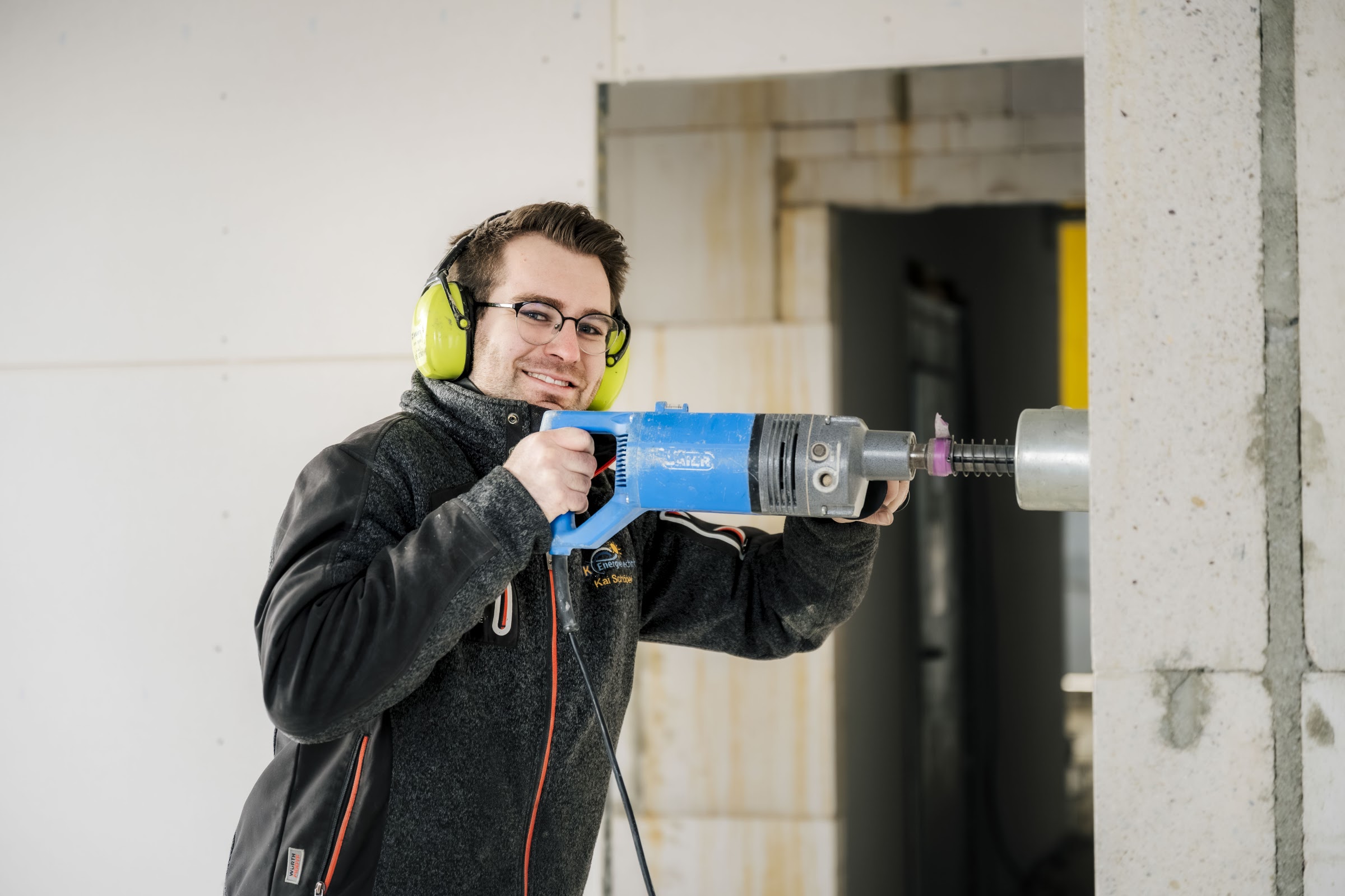 Elektroniker von TK-Energietechnik bohrt im Rohbau