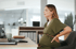 Pregnant woman experiencing back pain while sitting at an office desk.