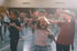 Eine Gruppe lachender Kinder tanzt mit erhobenen Armen in einer hellen Turnhalle.