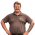 Mann mit Bart und braunem Poloshirt mit dem Logo "GARTEN VON KAEP" und tätowiertem Arm.