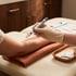 A gloved hand holds a medical injector pen against a person's arm on a treatment table.