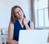 Woman holding shoulder in pain while using laptop, rotator cuff issue.