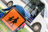 Blauer Schulranzen mit orangefarbenem Schulbus-Warnschild vor einem weißen Kleinbus mit geöffneter Tür.