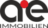 Schwarzes Logo "ae IMMOBILIEN" mit rotem Punkt über dem "a" auf dunkelgrünem Hintergrund.