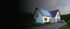 Modernes Haus mit Solarpaneelen auf dem Dach und Batterien im Vordergrund unter lila Licht.