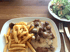 Ein Teller mit Schnitzel, Pilzrahmsoße und Pommes Frites; dazu ein Beilagensalat und Besteck.