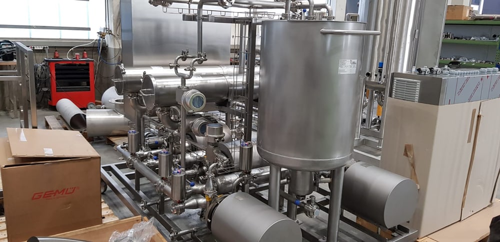 Edelstahlbehälter mit Rohrleitungen und Armaturen auf einem Montagegestell in der Werkstatt