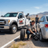 Towing Sandy flat tire change service replacing a flat tire on an SUV during a roadside emergency with a service truck standing by.