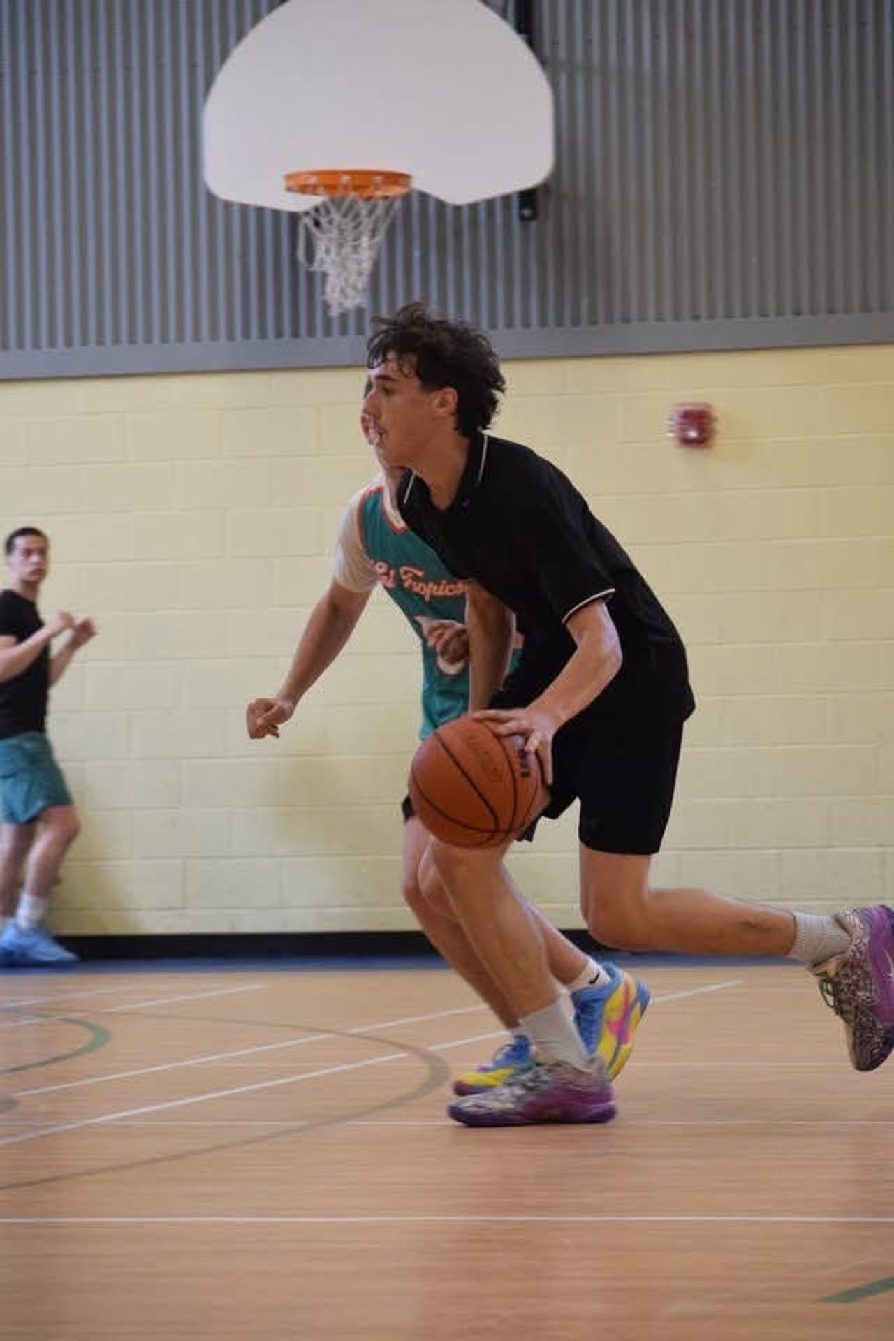 Un joueur de basketball avance vers le panier, ballon en main