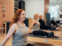 Drei Frauen trainieren lächelnd in einer Reihe auf Pilates-Reformern in einem hellen Studio.