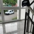Ein weißer Lieferwagen parkt draußen, durch ein Fenster im Treppenhaus gesehen, mit einer schwarzen Kappe "BLITZ" auf dem Geländer.