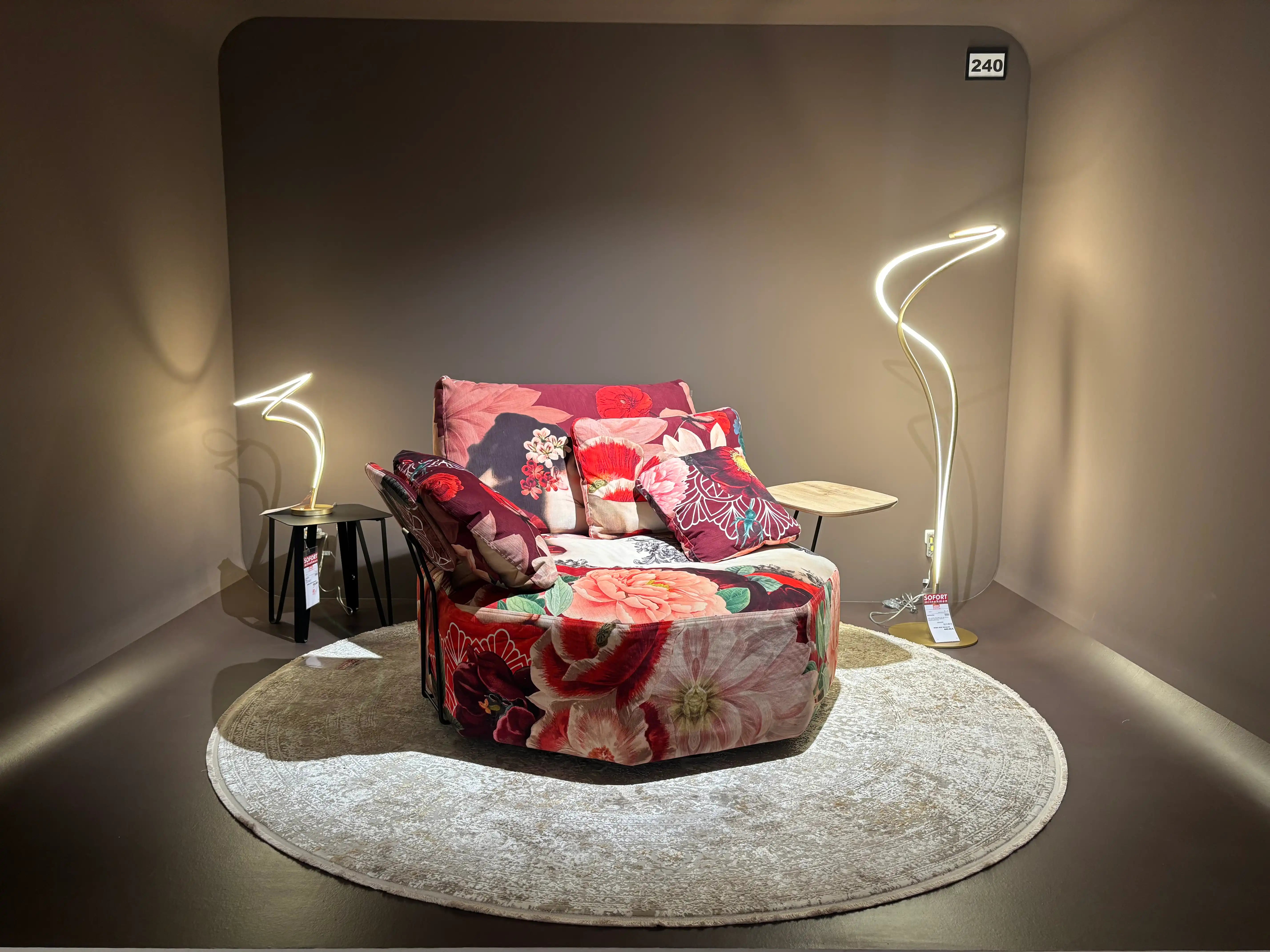 Drehsessel mit floralem Bezug in einer beleuchteten Showroom-Nische