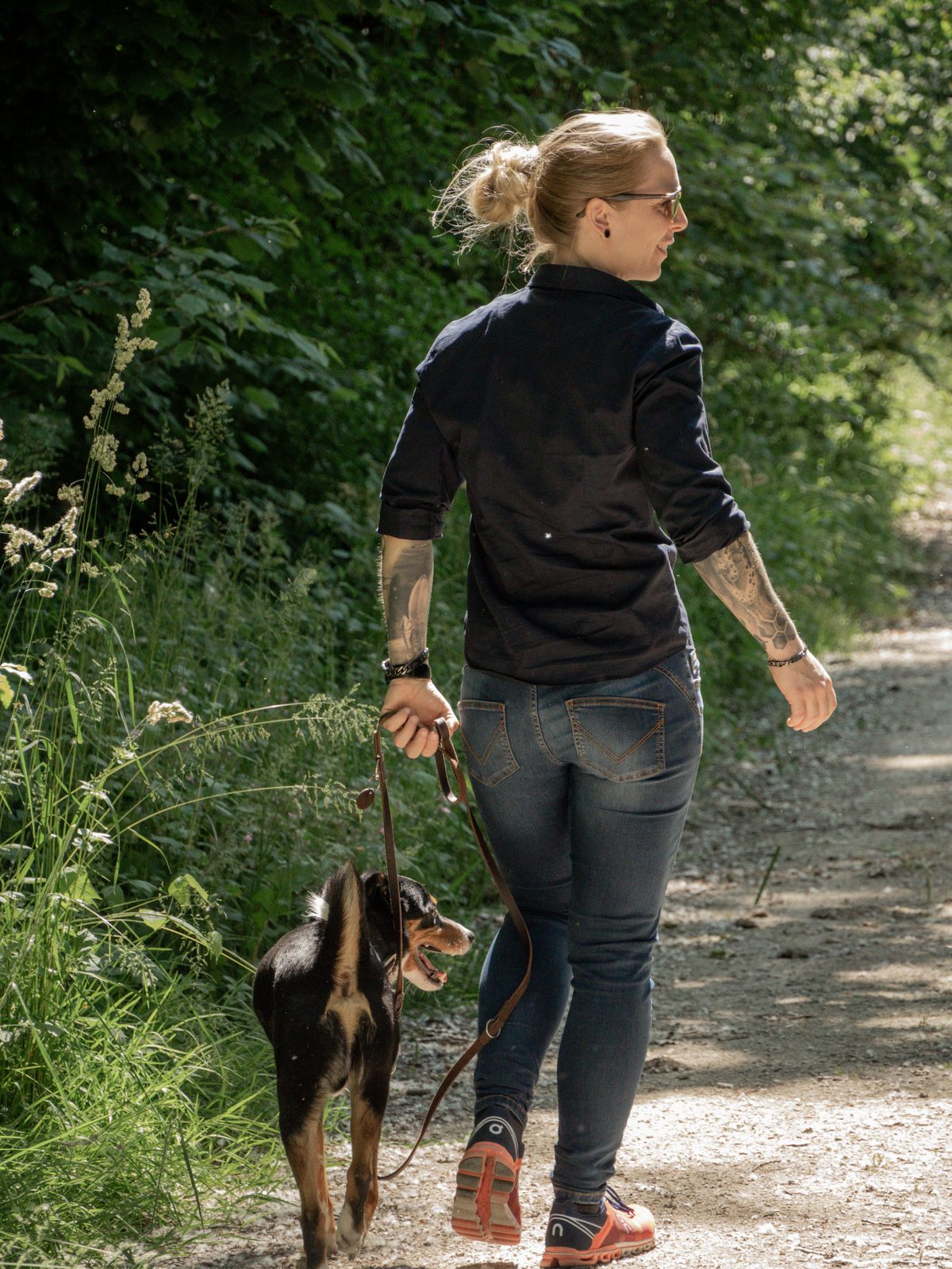 Chalina geht mit ihrem Hund auf einem sonnigen Waldweg
