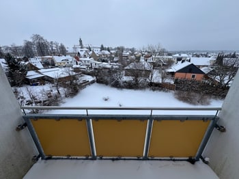 Blick vom Balkon über die verschneiten Dächer zur Kirche