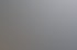 Eine Hand hält eine weiße Fernbedienung mit Pfeiltasten vor einem unscharfen Fenster.