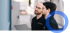 Zwei Männer, einer mit Laptop, schauen aufmerksam nach oben.