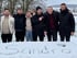 Sechs Männer in Winterjacken stehen lachend im Schnee beim Teamevent, im Vordergrund ein Schriftzug im Schnee