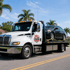 Towing Deltona flatbed towing service hauling a secured sedan on a rollback tow truck through a residential neighborhood