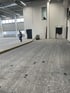 Mann geht in einer großen leeren Halle mit Betonboden und einer Absauganlage.
