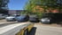 Gelber Abschleppwagen vor vier geparkten Autos auf einem sonnigen Parkplatz mit Bäumen.
