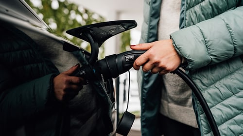 Driver plugging a portable EV charger cable into an electric car at a Lake Forest, CA home