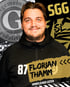 Mann mit Bart im schwarzen Kapuzenpullover, mit Text "87 FLORIAN THAMM SPORTLICHER LEITER" und Logos "SGG" und "SL".