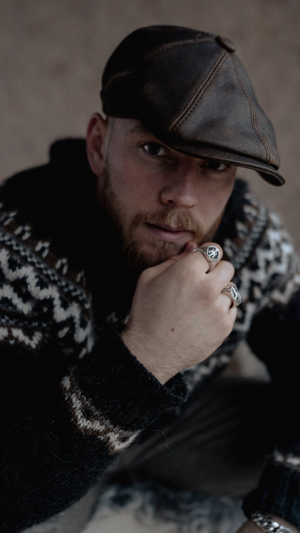 Mann mit Schiebermütze und Strickpullover