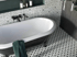 Freistehende Badewanne in einem Badezimmer mit gemusterten Wand- und Bodenfliesen.