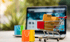Symbolbild für E-Commerce: Miniatur-Einkaufswagen mit Kartons vor Laptop mit Online-Shop – ideal für Onlinehandel und Shopify-Shop-Lösungen