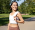Woman carrying a white towel over her shoulder in a sunny park.