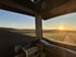 Aussicht aus dem Aufstelldach eines Reisewagens bei Sonnenuntergang – Naturpanorama mit Feldern und Weitblick beim Vanlife-Abenteuer