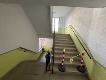 Treppenaufgang mit Handlauf, im Vordergrund eine Absperrung