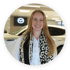 Junge blonde Frau in weißem Hemd und Leopardenmuster-Schal, lächelnd vor einem Mazda-Logo und Auto.