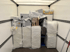 LKW-Ladefläche gefüllt mit verpackten weißen und grauen Möbelteilen, einige mit Folie umwickelt, andere in Kartons.