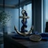 Bronzener Anker mit blauem Seil und einer runden Plakette mit Fischsymbol auf dunklem Holztisch.