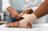 Medical pro bandages ankle, highlighting workers’ compensation care.