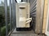 Beige Klimaanlage an einer Holzfassade mit Rohren auf einem Balkon.