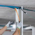 Hände in Arbeitshandschuhen verlegen orangefarbene und blaue Kabel in einem weißen Kabelkanal an der Decke.