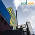Rauch steigt aus dem Schornstein eines großen Heizkraftwerks mit BIO|HKW-Logo.
