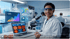 A female scientist in a lab coat and safety glasses sits by a laptop and microscope with 25% growth data charts overlay.
