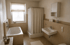 Badezimmer mit Badewanne, Dusche mit Vorhang, Waschbecken und hellem Fenster.