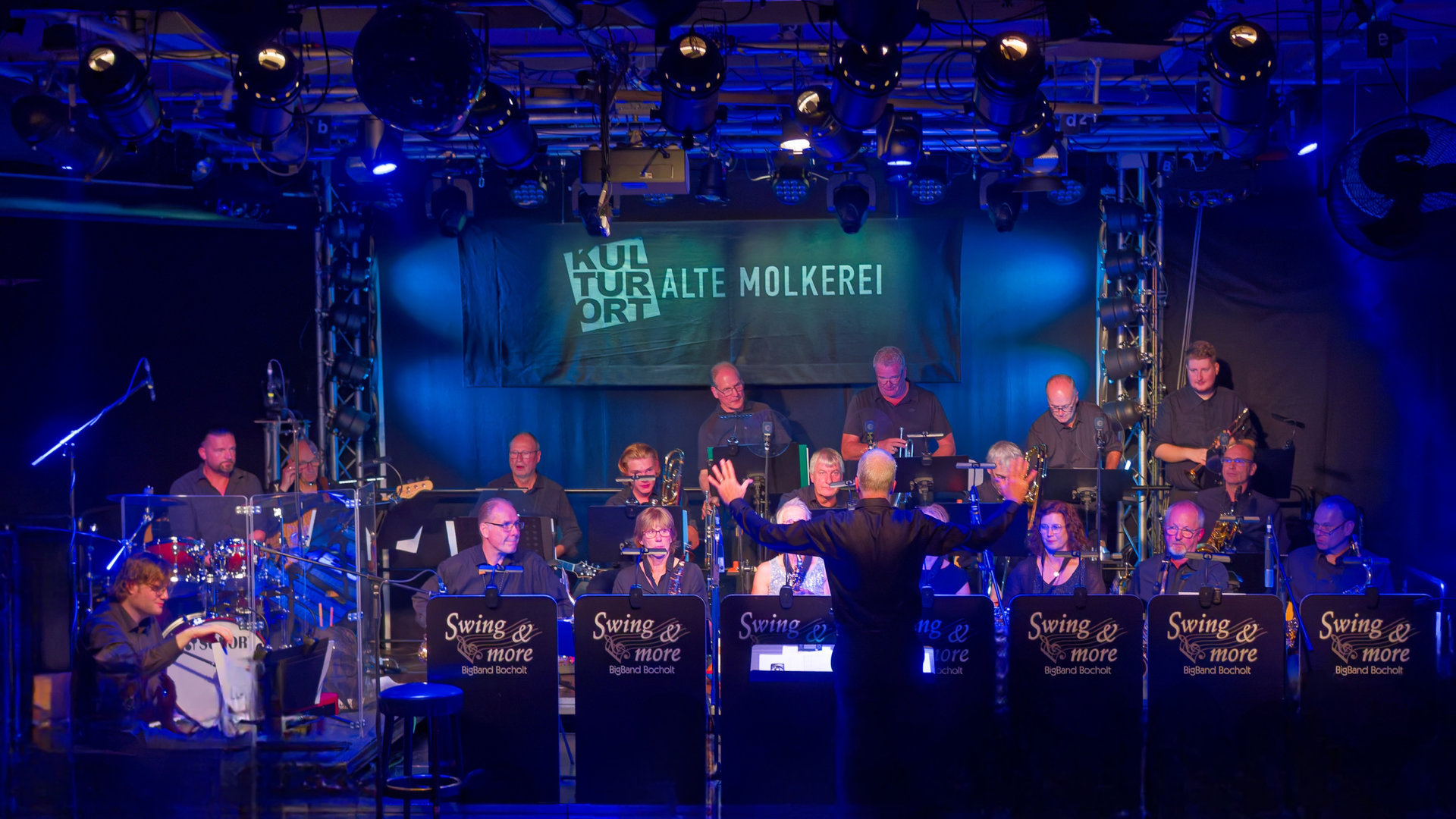 Gruppenfoto der Swing & More BigBand Bocholt mit Instrumenten auf der Bühne