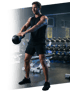Ein Mann in schwarzer Sportkleidung macht Kettlebell-Schwünge im Fitnessstudio.