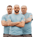 Drei Männer in hellblauen T-Shirts mit verschränkten Armen blicken nach vorne.