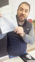 Can Pekesen hält ein Formular mit handgeschriebenen Notizen und gelben Markierungen hoch.