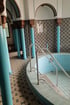 Runder Pool mit blauen Fliesen und silbernen Handläufen, umgeben von blauen Säulen und gemusterten Fliesenwänden.