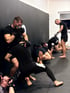 Männer in schwarzen Hemden und Handschuhen trainieren Mixed Martial Arts in dem KIQ Studio.