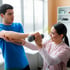 A patient uses dumbbells with a physical therapist.